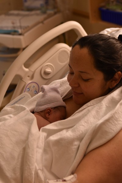 A mother holding her newborn close in a hospital bed